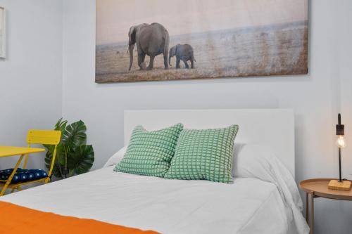 a bed with two pillows and a picture of an elephant at PR Rentals Ocean Park Beach Apartment 2 in San Juan