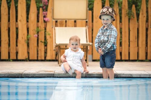 a boy and a baby sitting next to a swimming pool at Ledro Mountain Chalet in Ledro
