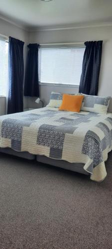 a bedroom with a large bed with blue curtains at Ohope Lifestyles in Ohope Beach