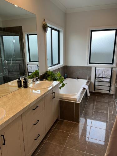 a bathroom with a tub and a sink and a bath tub at Pool, Spa pool, Private, Modern, Clive! in Clive