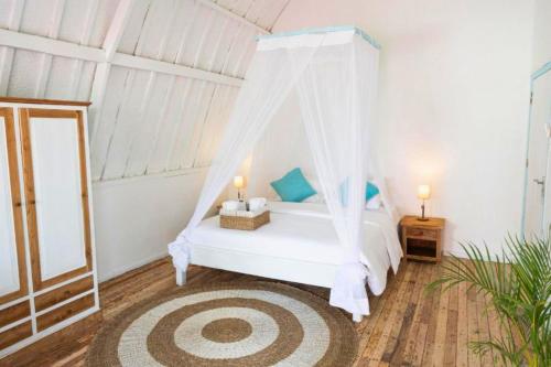 a bedroom with a white bed with a canopy at Cleosa 2 BR Cozy Bungalow Family ZN301 in Gili Air