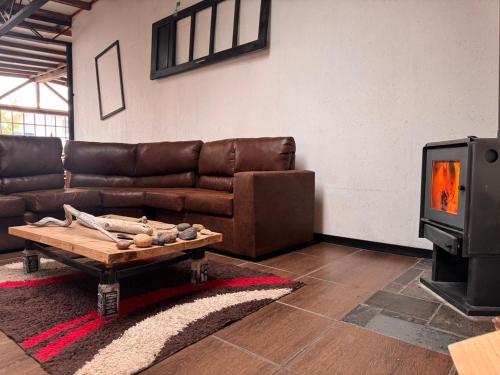 a living room with a leather couch and a tv at El Sendero in Puerto Natales