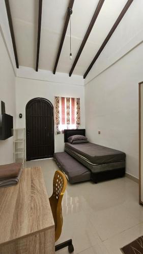 a bedroom with two beds and a table in it at Cute Room at Pondok Raima SYARIAH in Gresik