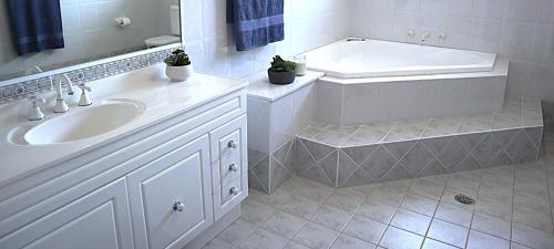 a white bathroom with a tub and a sink at Bella Callala Holiday Home in Callala Bay