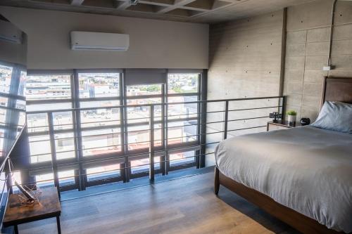 a bedroom with a bed and large windows at LOFT Apartment Downtown Area in Tijuana