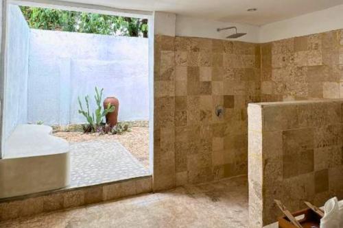 Un baño con bañera y ducha con ventana. en Quacey 1 BR Deluxe Room ZN302, en Gili Air