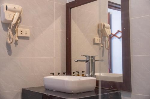 baño con lavabo, espejo y teléfono en Villa Namkhan River, en Luang Prabang