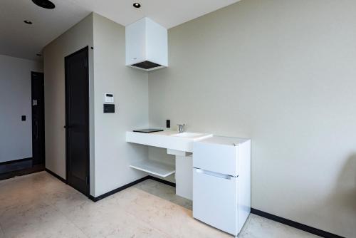 a white kitchen with a sink and a refrigerator at Cottage TAIZA in Kyotango