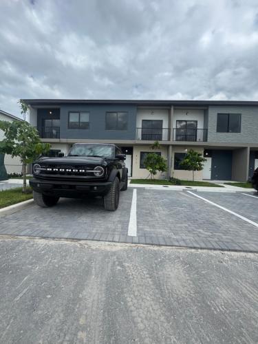 a black truck parked in a parking lot in front of a building at Modern room with kitchen and backyard access in Homestead