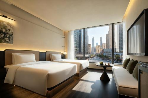 two beds in a hotel room with a large window at Yomanjo International Hotel - Prime Tianhe CBD Downtown Convenient Metro Access Short Ride to Canton Fair Diverse Room Types Free High Speed Wi-Fi 24 Hour Service in Guangzhou