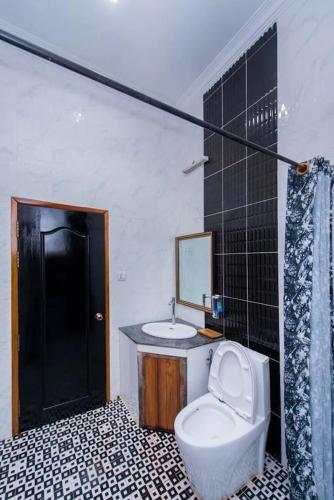 un bagno con un water, un lavandino e uno specchio di Soksan Villa a Battambang