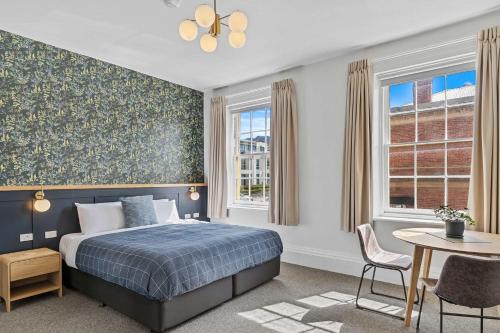 a bedroom with a bed and a table and chairs at Portsea Place - designer king studio and parking in Hobart