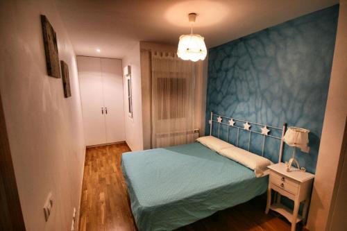 a bedroom with a bed and a blue wall at El Mirador del Rioja, Zona Laurel in Logroño