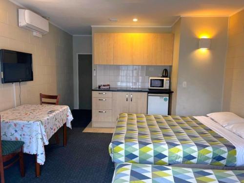 ein Hotelzimmer mit zwei Betten und einer Küche in der Unterkunft Takanini Park Motor Lodge in Auckland
