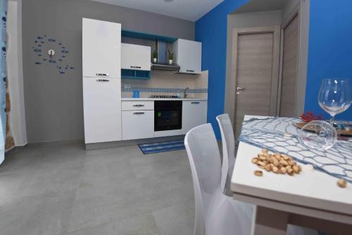 a kitchen with a table with a glass of wine and chairs at Maresol in Trappeto