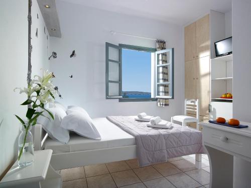 biała sypialnia z łóżkiem i oknem w obiekcie Galanis Rooms w mieście Adamas