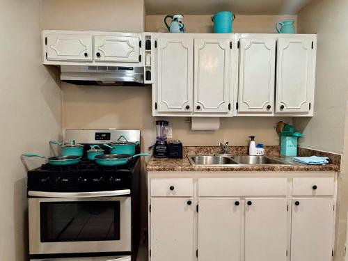 a kitchen with white cabinets and a stove and a sink at Casita-La Casa Contenta in El Paso
