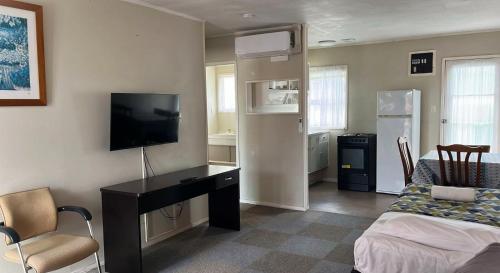 a room with a desk with a television and a bed at Takanini Park Motor Lodge in Auckland