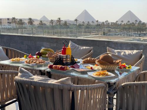 a table with food on it with pyramids in the background at New Galleria Pyramids view inn in Cairo