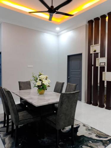 a dining room table with chairs and a vase of flowers at HomeStay Rafiza in Jertih
