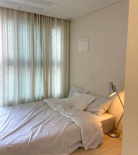 une chambre avec un lit avec des draps blancs et une fenêtre dans l'établissement Modern, Natural Studio near Sindorim Station, New Building, à Séoul