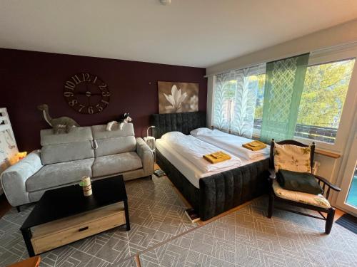 a bedroom with a bed and a couch and a clock at Leukerbad TOP, Thermalquellen, Skigebiet in Leukerbad