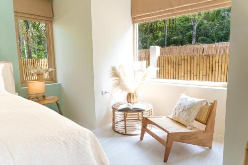a bedroom with a bed and a chair and a window at The Palm Villa in Ban Ai Dao
