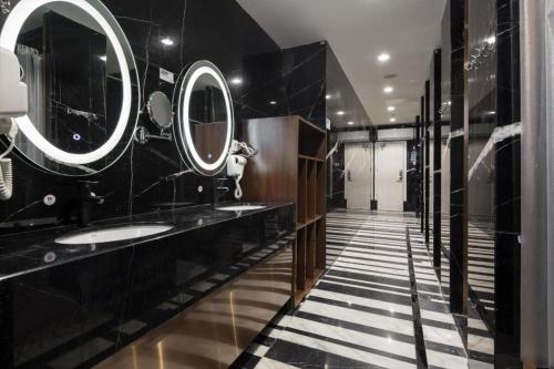 a black bathroom with two sinks and mirrors at Shenzhen Nan Fei Yuan Hotel in Shenzhen
