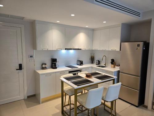 a kitchen with a refrigerator and a table and chairs at Luxury Condo The City Phuket in Heart of Phuket in Kathu