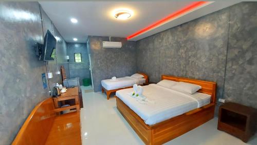 a bedroom with two beds and a television in it at J House Has Love in Sukhothai