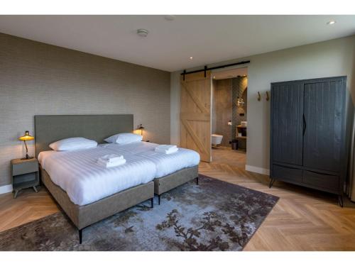a bedroom with a large bed and a bathroom at Modern villa in De Cocksdorp near the beach in De Cocksdorp