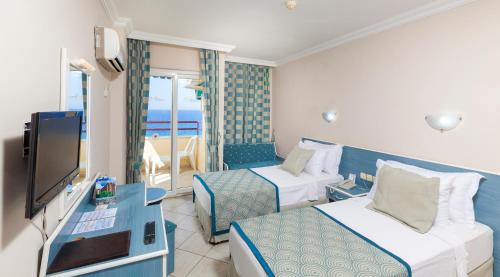 a hotel room with two beds and a flat screen tv at Galaxy Beach Hotel Alanya in Mahmutlar