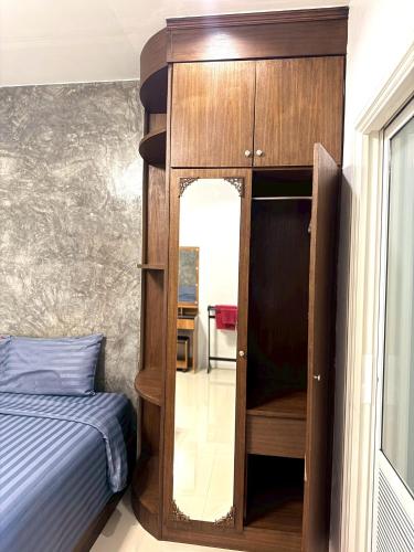 a bedroom with a bed and a wooden cabinet with a mirror at Buncha Place in Bang Tao Beach