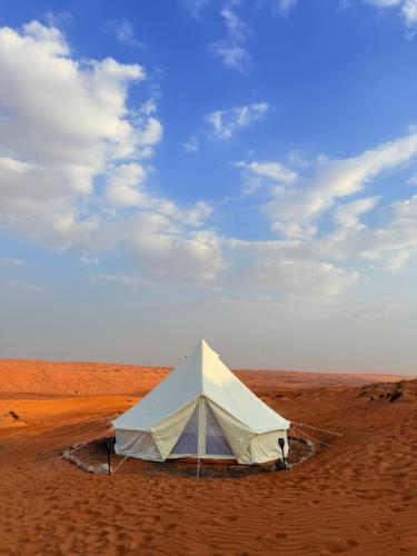 une tente blanche au milieu du désert dans l'établissement Bedouin Stars, à Ḩawīyah