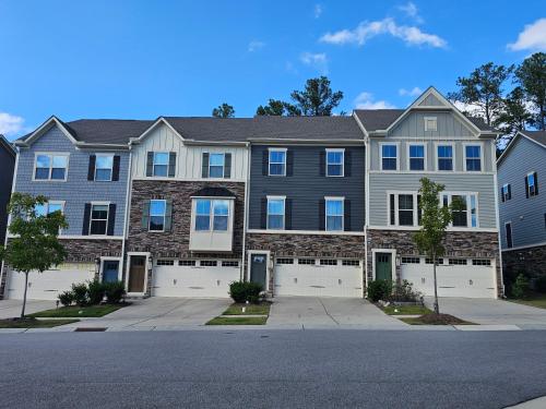 a large brick house with white garage doors at Impeccable 3BR Townhouse Near RDU & Hospitals in Cary