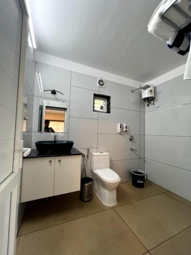 a bathroom with a toilet and a sink and a mirror at Pakalakam Resorts in Cheruppulasseri