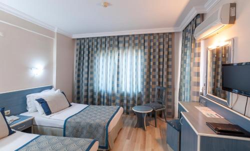 a hotel room with two beds and a flat screen tv at Galaxy Beach Hotel Alanya in Mahmutlar