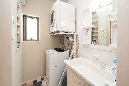 a laundry room with a sink and a washer and dryer at kafuulivimg sobe in Yomitan