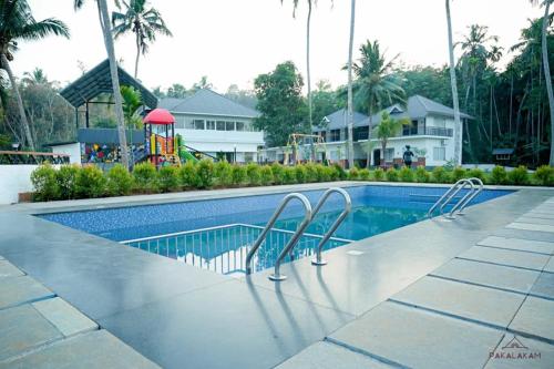 a swimming pool with a slide and a playground at Pakalakam Resorts in Cheruppulasseri