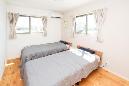two beds in a room with two windows at kafuulivimg sobe in Yomitan