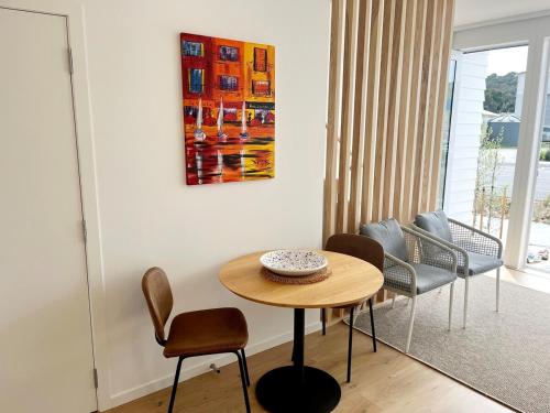 a room with a table and chairs and a painting at Villa in the heart of Matakana in Matakana