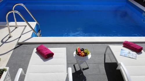 a bowl of fruit sitting on a table next to a pool at Villa M in Split