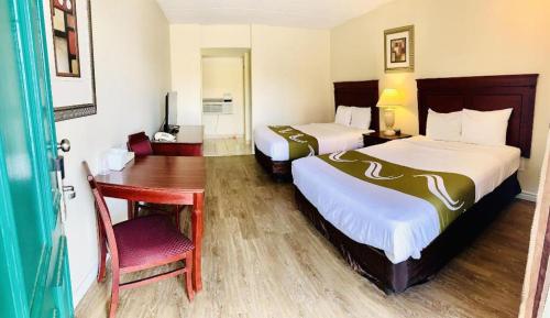 a hotel room with two beds and a desk at Niagara Best Inn in Niagara Falls