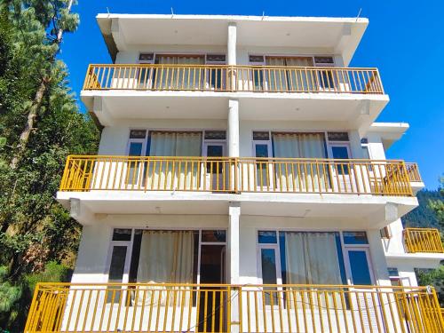 a tall white building with yellow balconies on it at Aurora Grove in Manāli