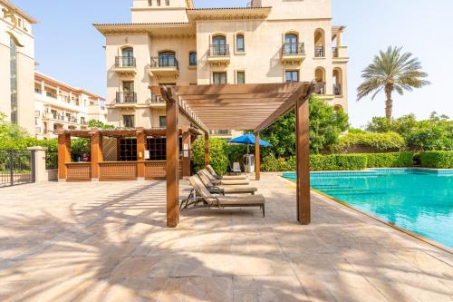 a gazebo with lounge chairs next to a pool at Stylish 1BR - Grand Royale Luxe Escape in Abu Dhabi