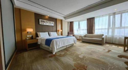 a hotel room with a bed and a couch and window at Ramada by Wyndham Wuhu in Wuhu