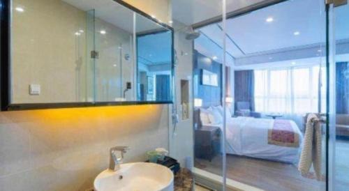 a bathroom with a sink and a bedroom at Ramada by Wyndham Wuhu in Wuhu