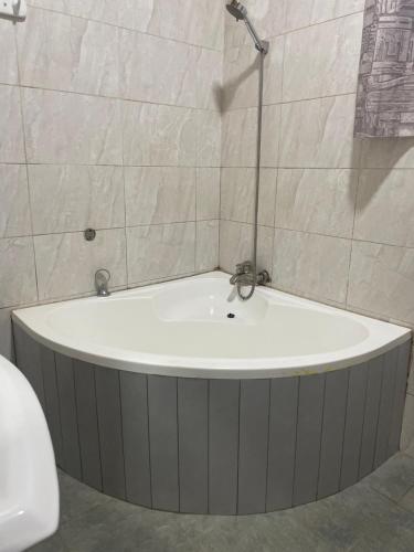 Una bañera en un baño con una pared de azulejos. en Émeraude Kigali, en Kigali
