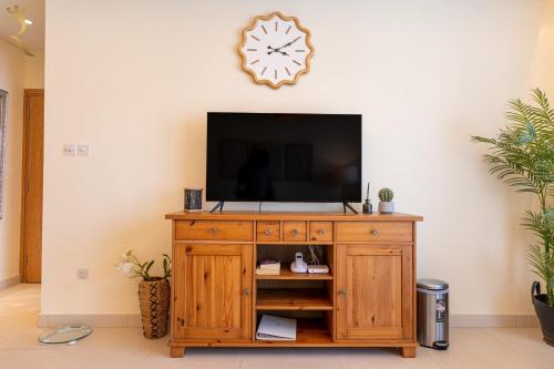 a television on a wooden cabinet in a living room at Stylish 1BR - Grand Royale Luxe Escape in Abu Dhabi