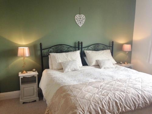 a bedroom with a large white bed with two lamps at The Haven in Rothbury